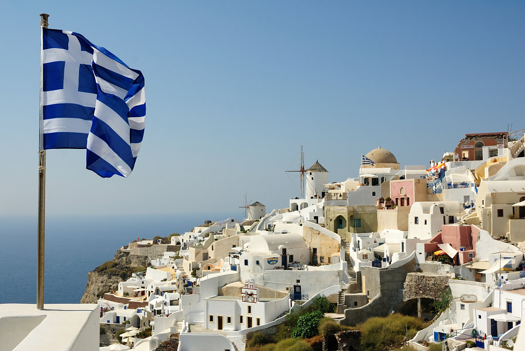 The flag and the Greek windmills - Santorini, Greece